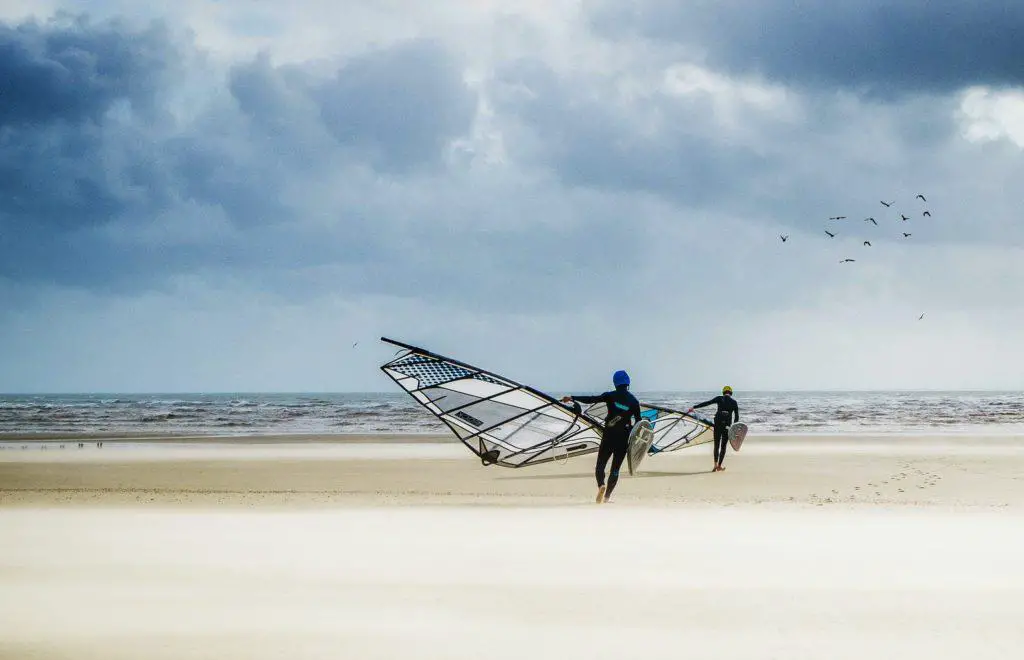 windsurfers walking towards ocean